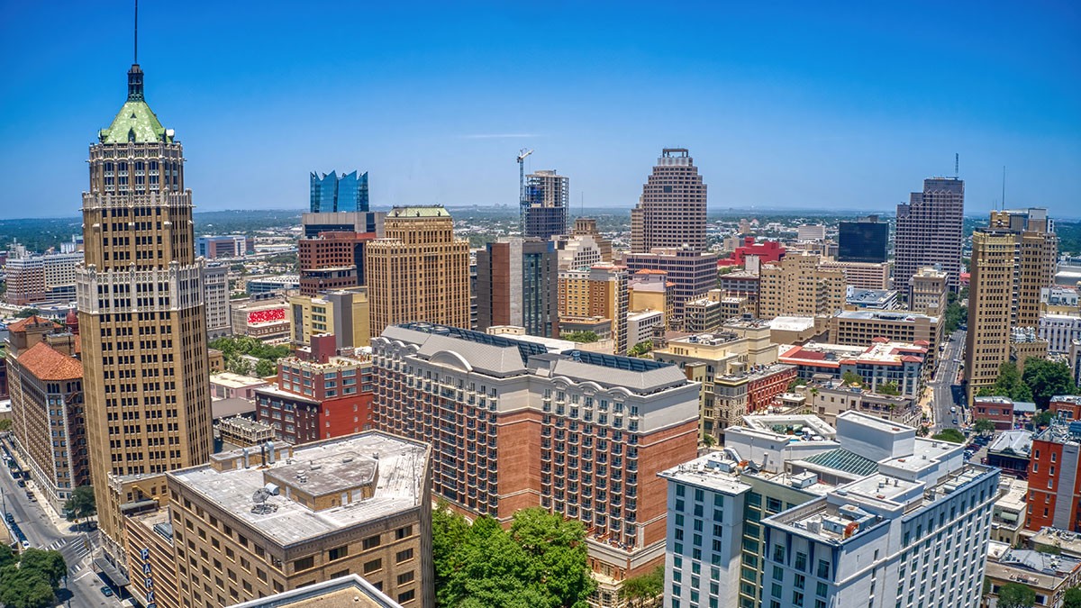 Aerial view of a city skyline with a mix of historic and modern buildings under a clear blue sky.
