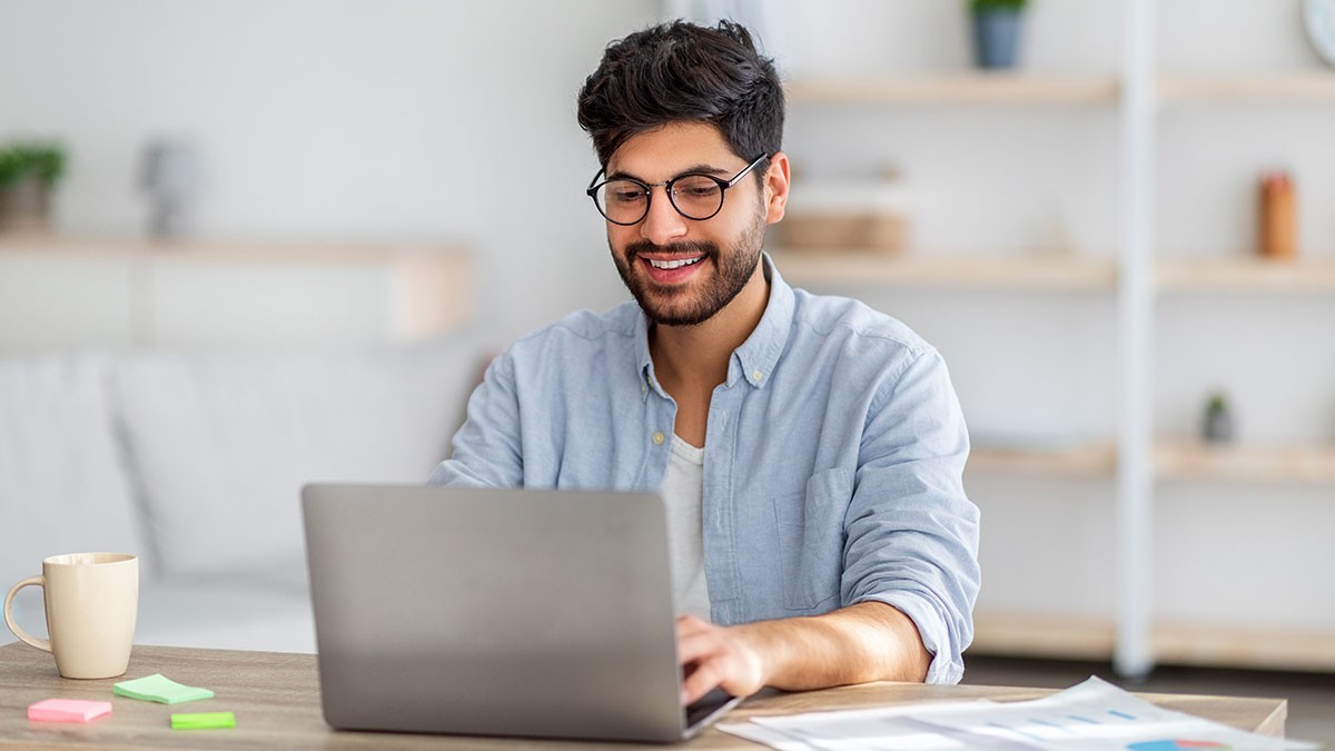 Young man wearing glasses typing on his laptop