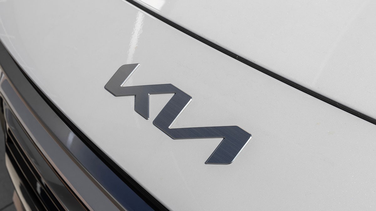 Close-up of a silver car logo on a white vehicle hood, displaying a stylized, angular design.