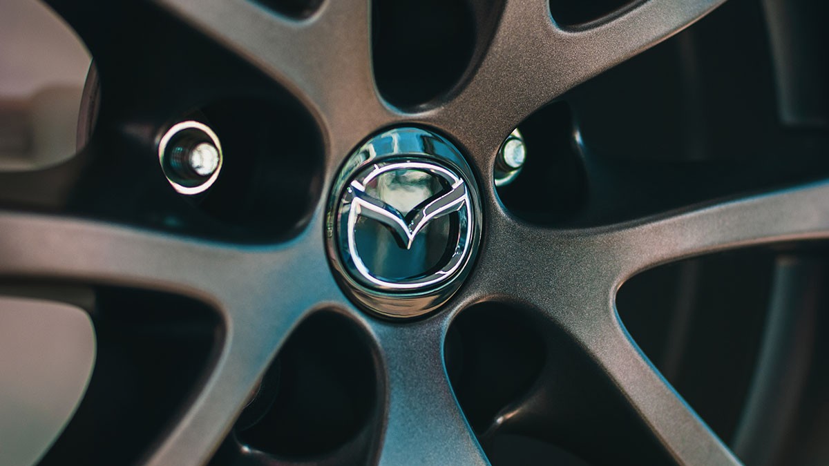 Close-up of a Mazda car wheel, featuring the Mazda logo at the center of a metallic, multi-spoke rim design.