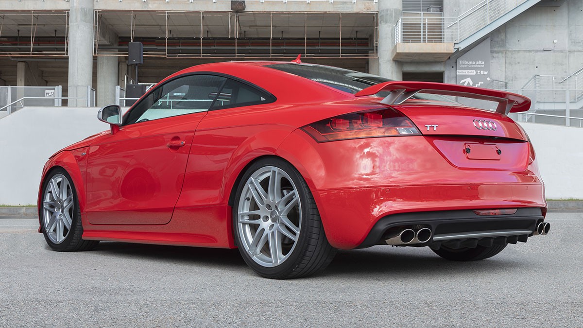 Red Audi TT coupe, rear three-quarter view with spoiler, quad exhausts and silver alloy wheels.