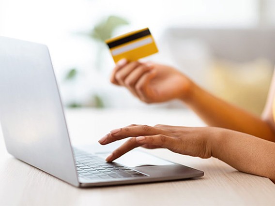 Closeup of person using laptop and holding credit card