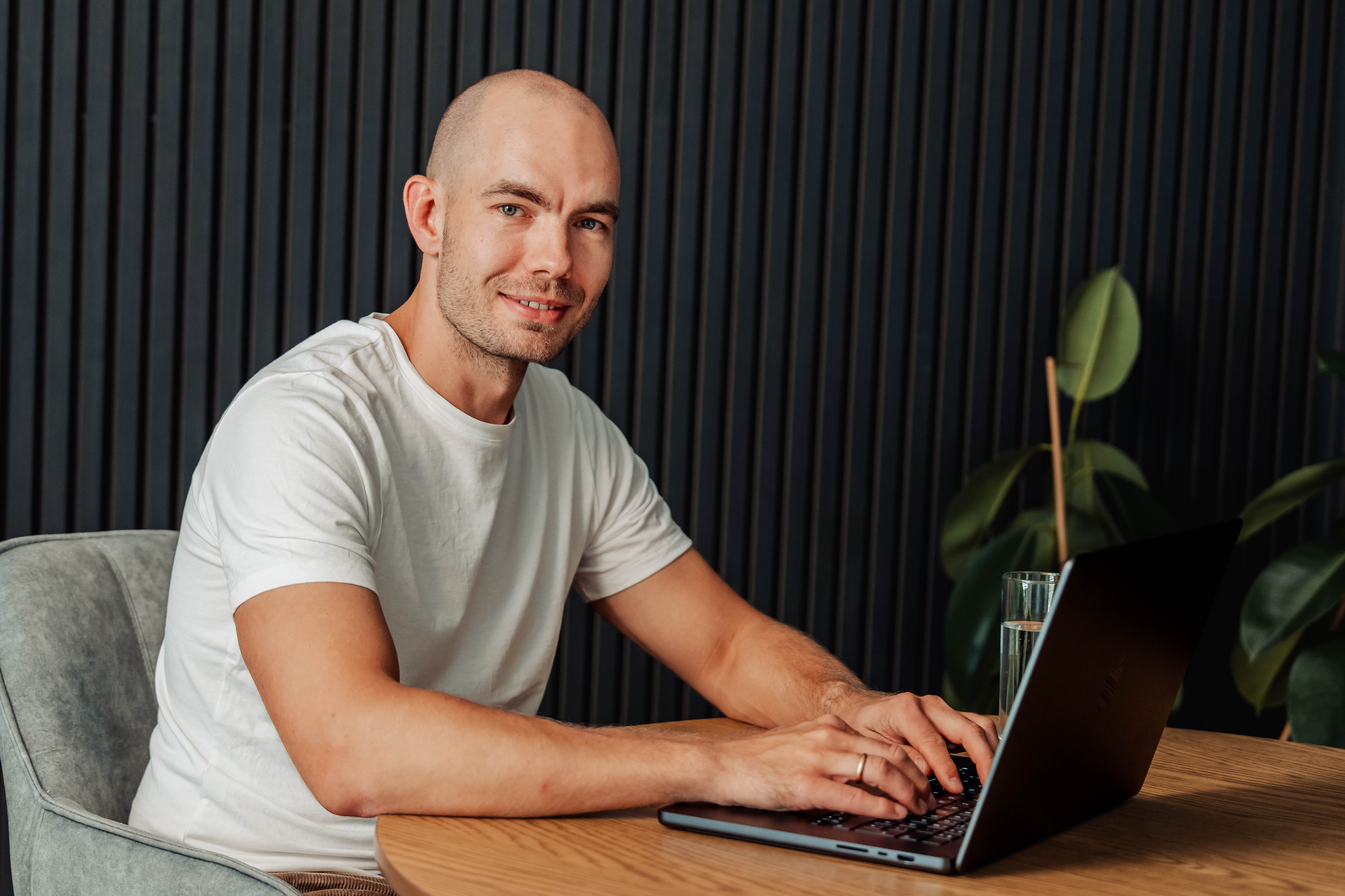 Thomas Groissberger sitzt mit einem Laptop am Tisch und blickt in die Kamera.