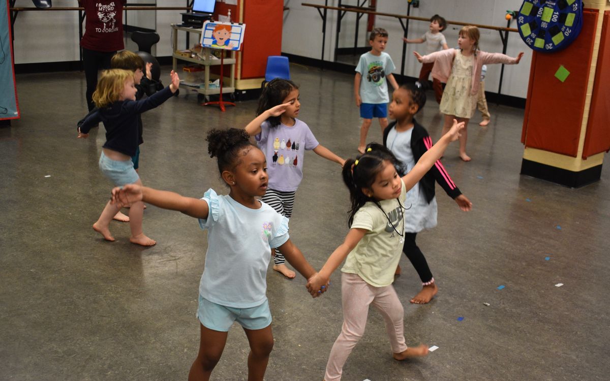 Preschoolers holding hands and dancing in a KWEST creative movement activity
