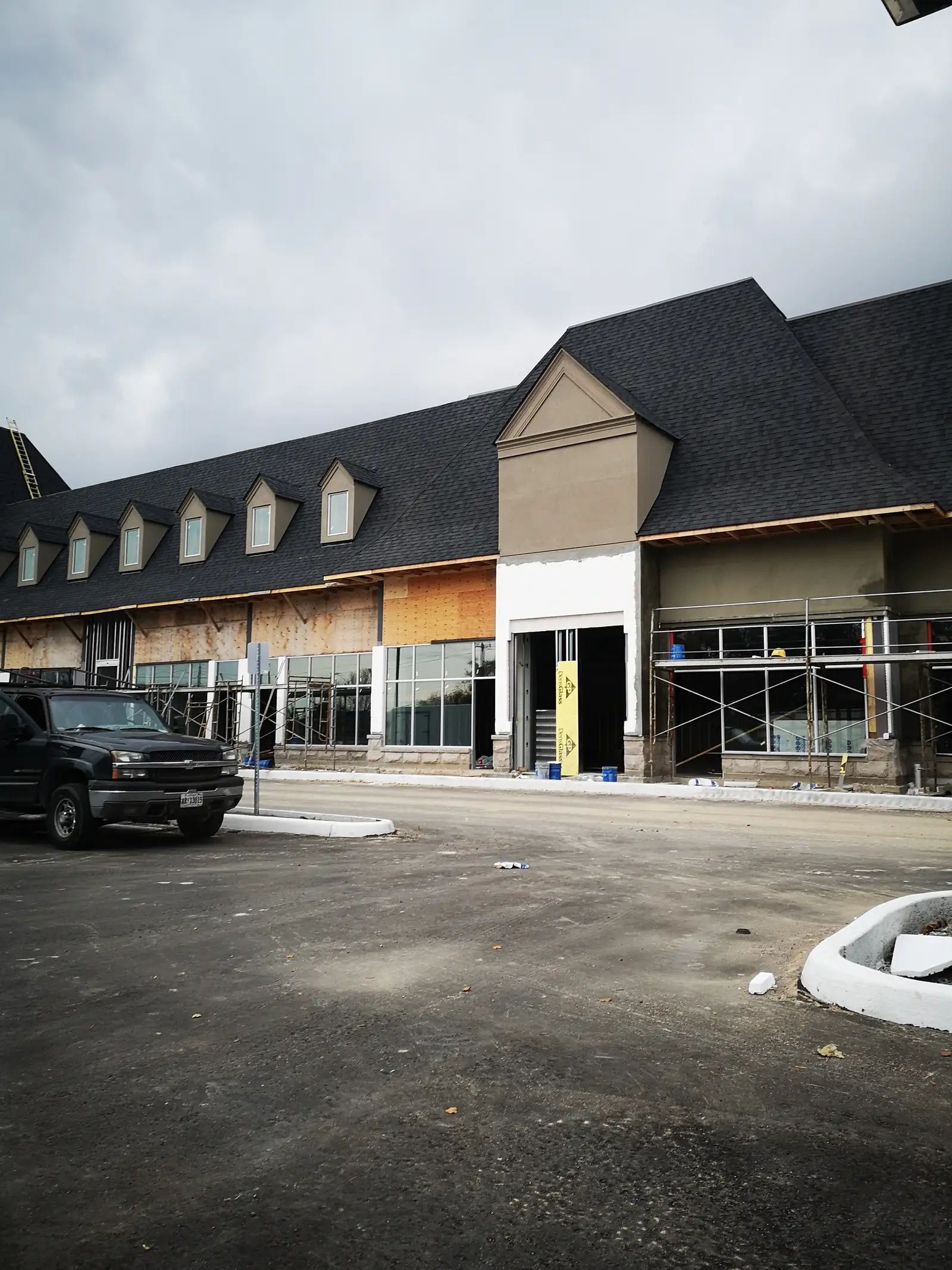 Wider view of the large structure, including roof geometry, dormers, and broad openings