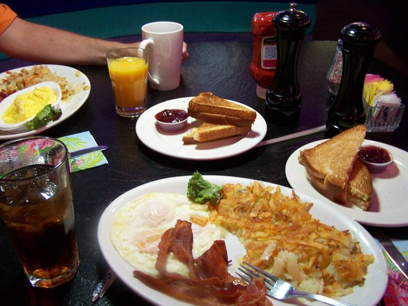 A breakfast table at the Peppermill with plates of eggs, bacon, hash browns and toast, orange juice and coffee