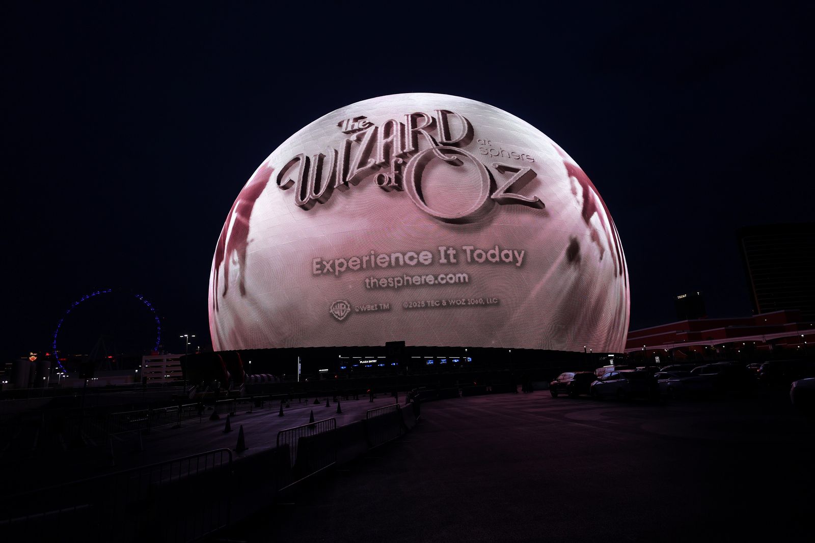 Sphere lit up at night with a Wizard of Oz at Sphere display on its outer screen