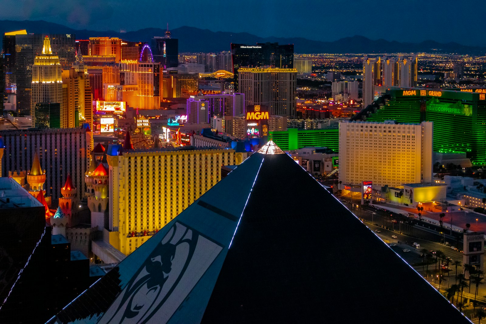 Las Vegas Strip resort towers glowing in neon at night, seen from a high-rise lounge at the south end of the Strip