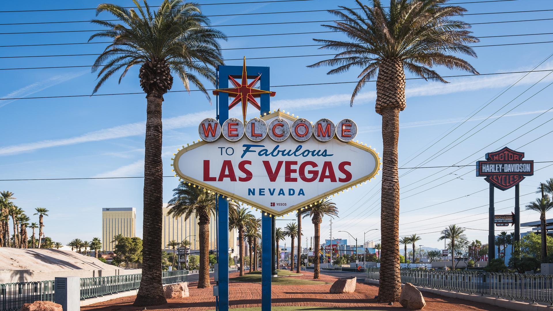 The Welcome to Fabulous Las Vegas sign between two tall palm trees on a sunny day