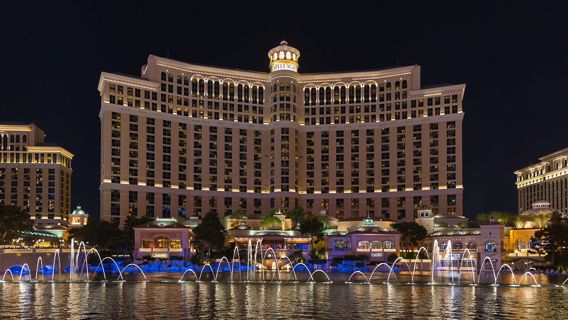 Bellagio hotel tower lit up at night above its lake, with the fountains rising in front