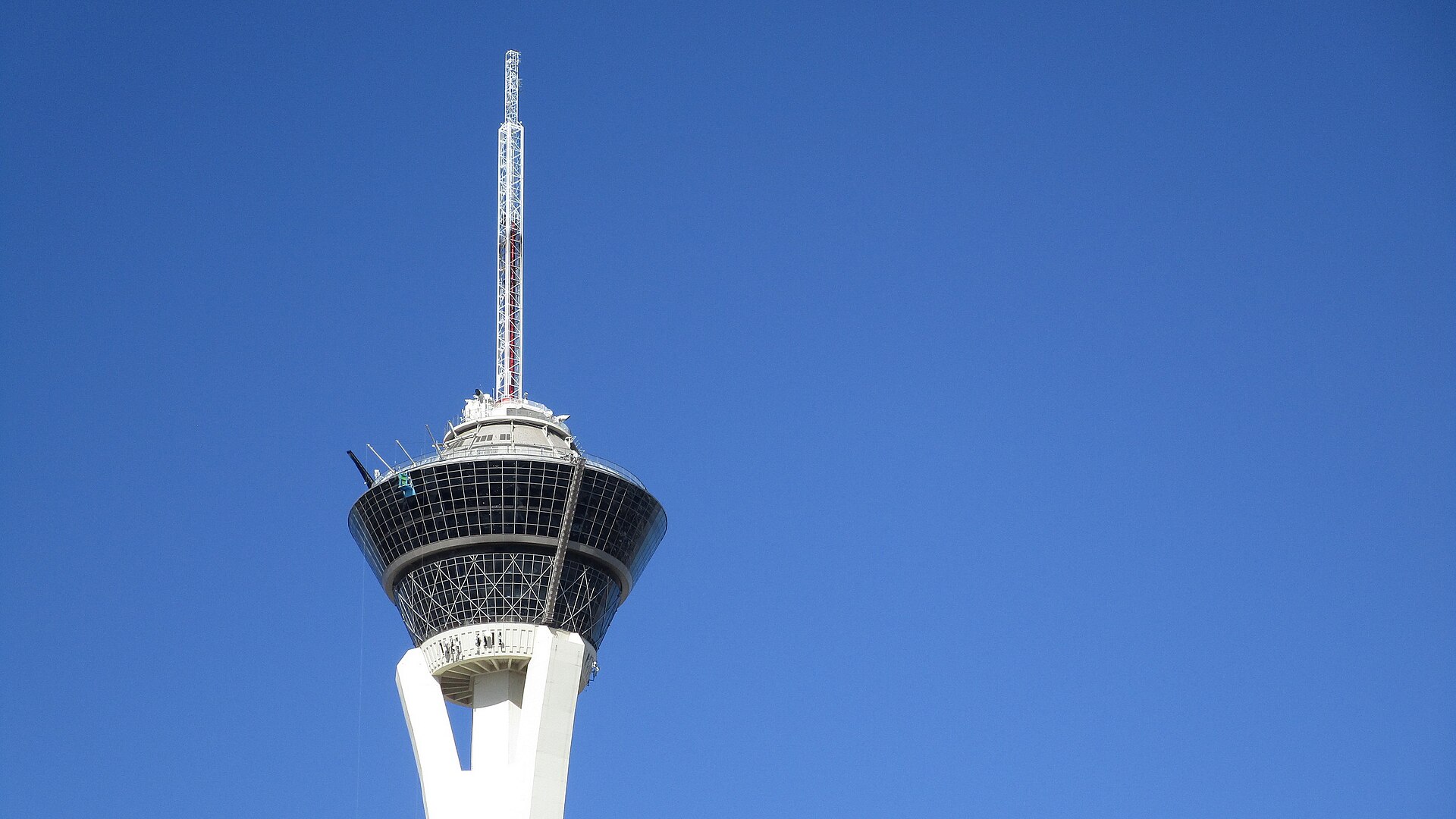 Top of The STRAT tower with its observation pod and the Big Shot ride mast against a blue sky