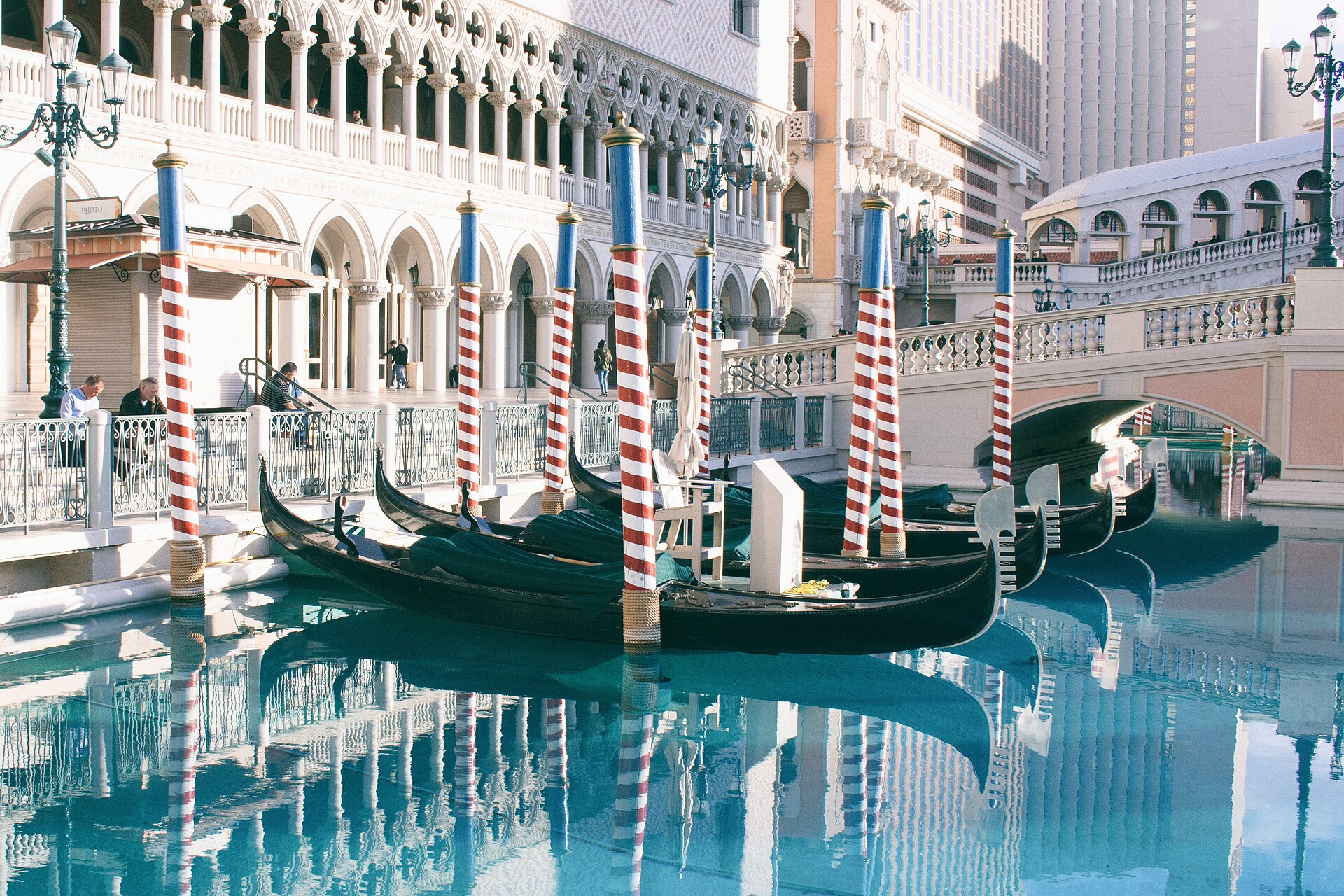 Black gondolas moored between red and white striped poles on the Venetian's outdoor canal