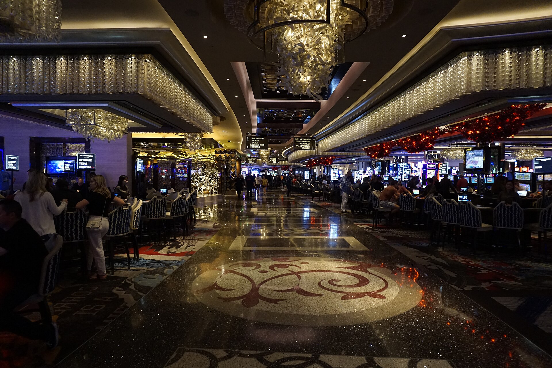 The Cosmopolitan casino floor with a patterned carpet and crystal chandeliers glowing overhead