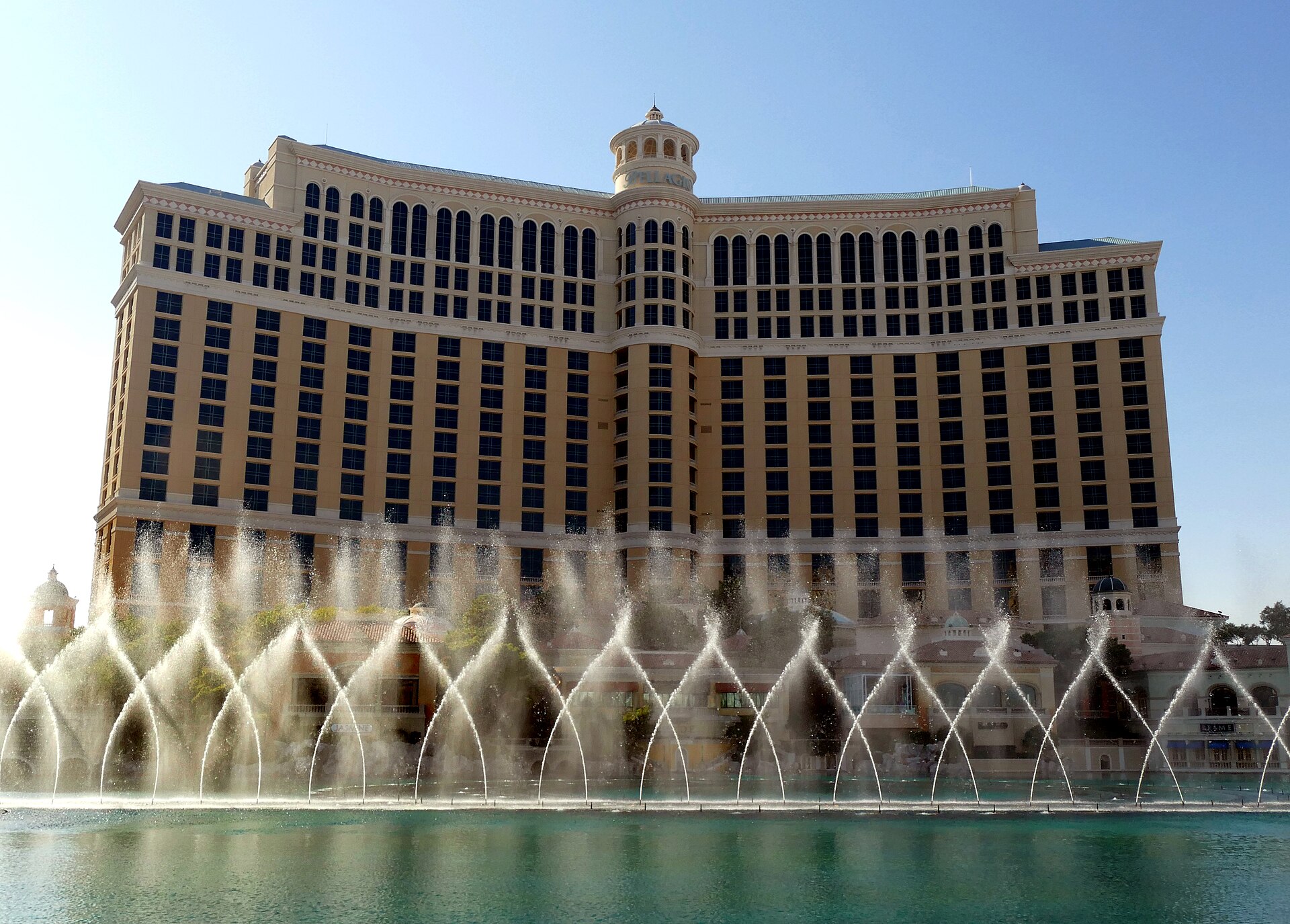 Arcs of water from the Fountains of Bellagio in daylight, with the curved hotel tower behind