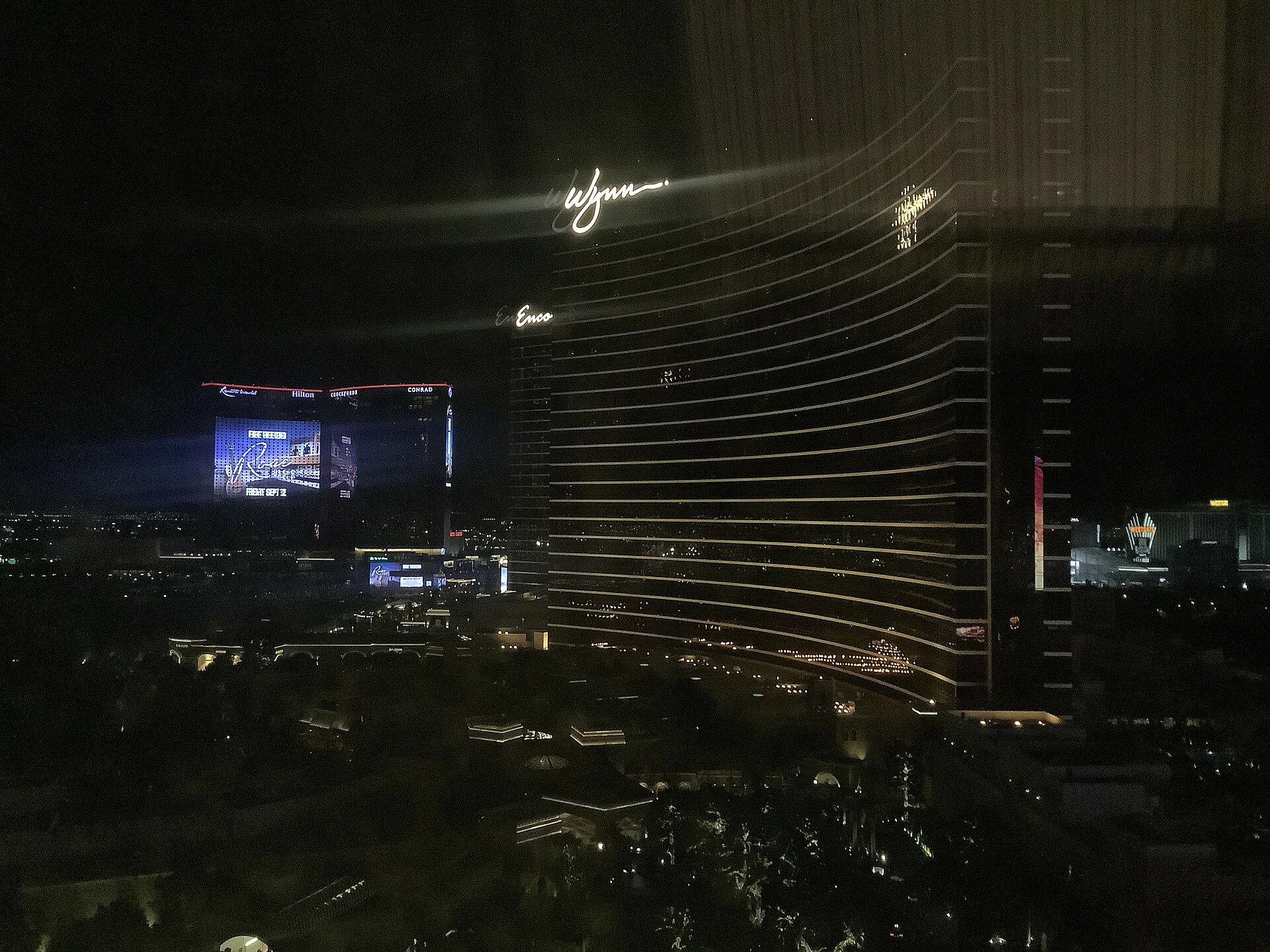 Wynn and Encore towers lit at night with Resorts World behind them on the North Strip