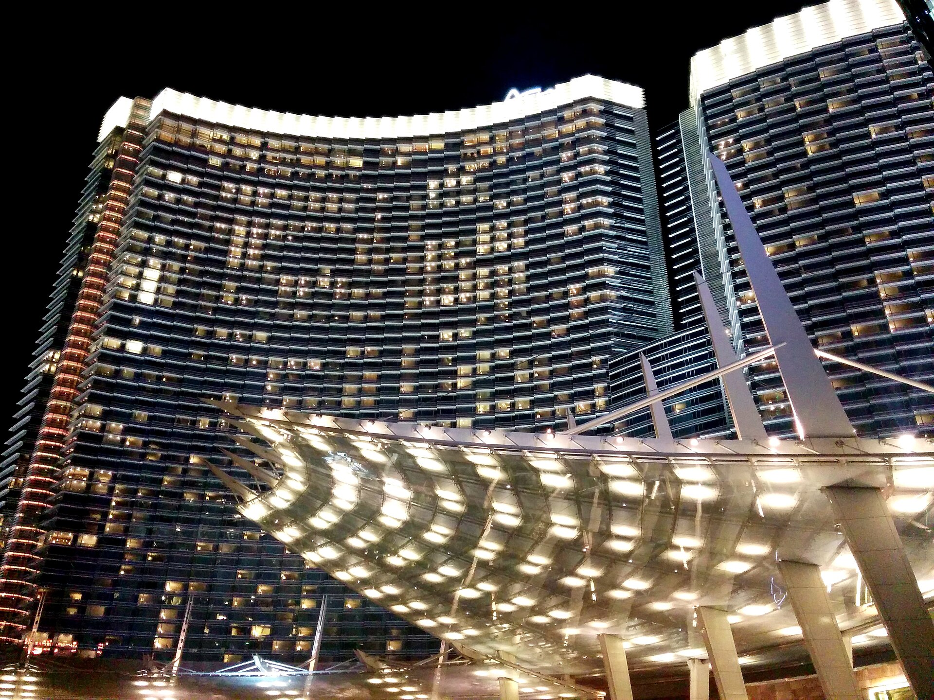 ARIA Las Vegas hotel towers lit at night above the curved glass canopy of the entrance