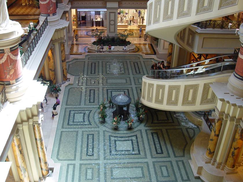 Looking down inside The Forum Shops at Caesars Palace at curved spiral escalators, columns and a patterned marble floor