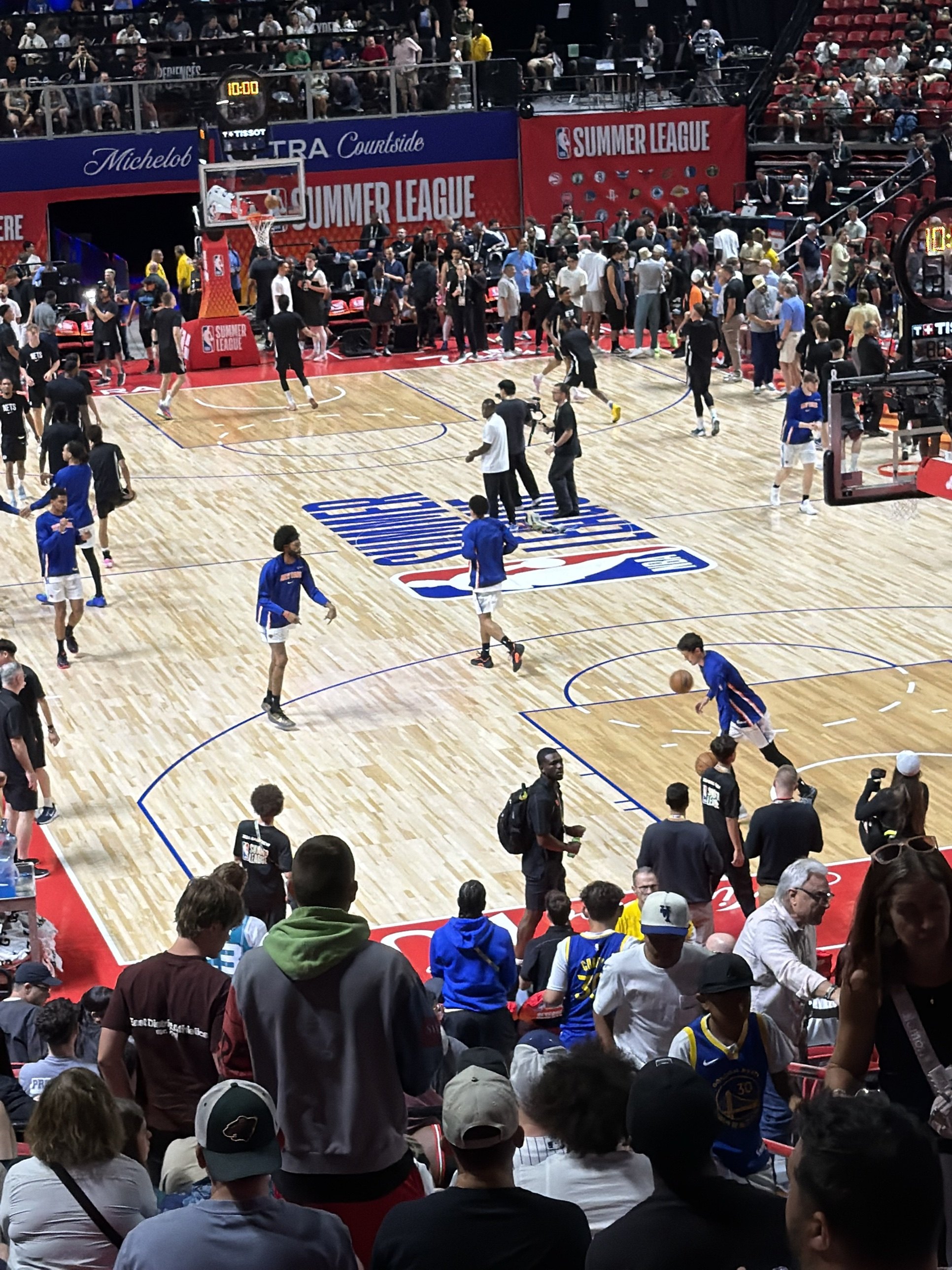 Players warming up on the NBA Summer League court inside the Thomas and Mack Center, with fans filling the lower seats
