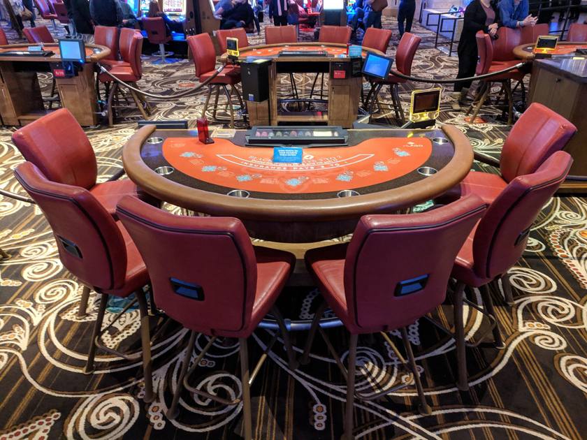 An empty blackjack table with burgundy chairs, set for play