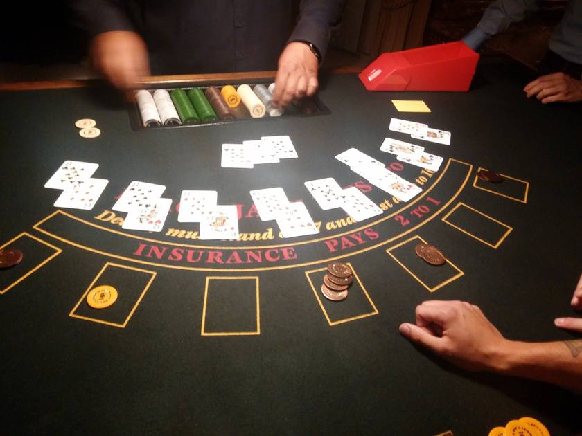 A dealer’s hands distributing cards on a blackjack table, with chips in front of the players