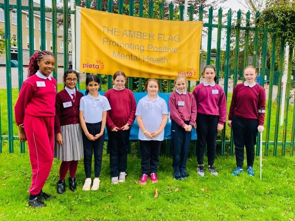 Pupils standing in front of the Amber Flag banner on the school railings