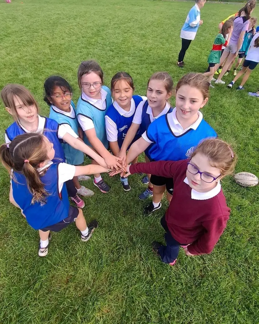 Pupils in a circle with their hands joined in the middle before a game