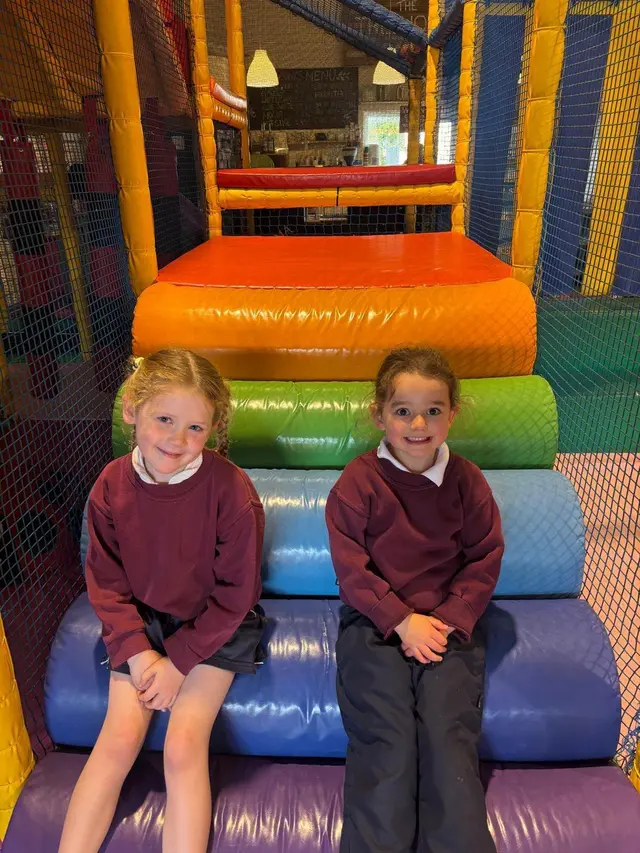 Two pupils in the school tracksuit: maroon top and white polo shirt, with navy shorts and navy tracksuit bottoms