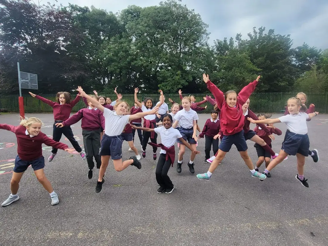Pupils jumping and stretching out their arms on the school yard
