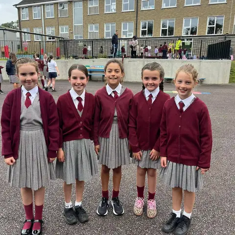 A group of pupils on the yard on the first day back, with the school building behind