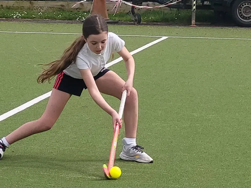 A pupil dribbling a hockey ball on the astro