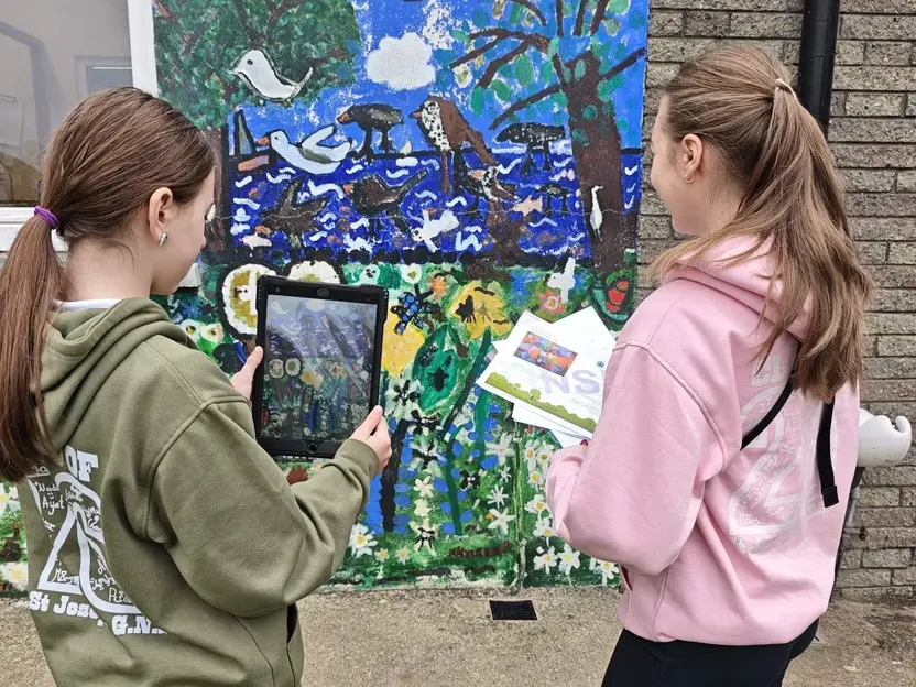 Two pupils photographing a mural with a tablet