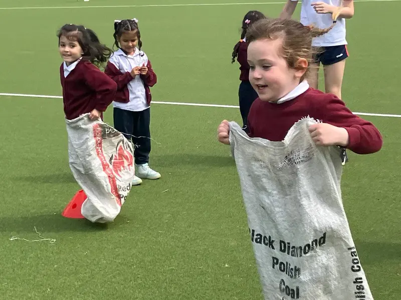 Junior pupils in a sack race on the astro pitch