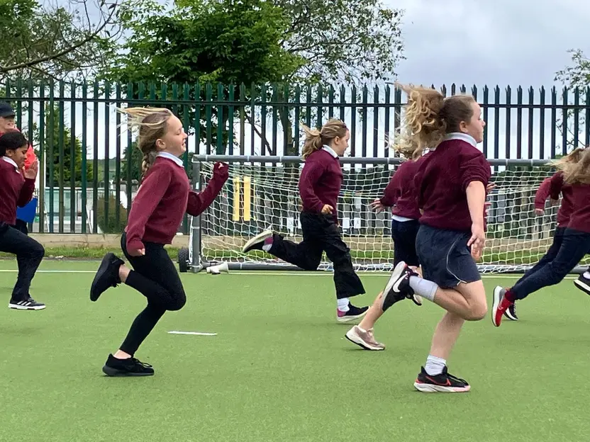 Pupils in school uniform running on the astro pitch