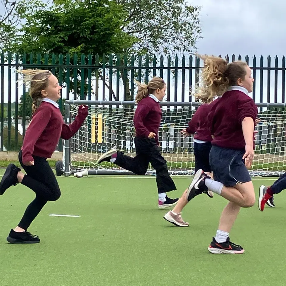 Pupils in school uniform running on the astro pitch