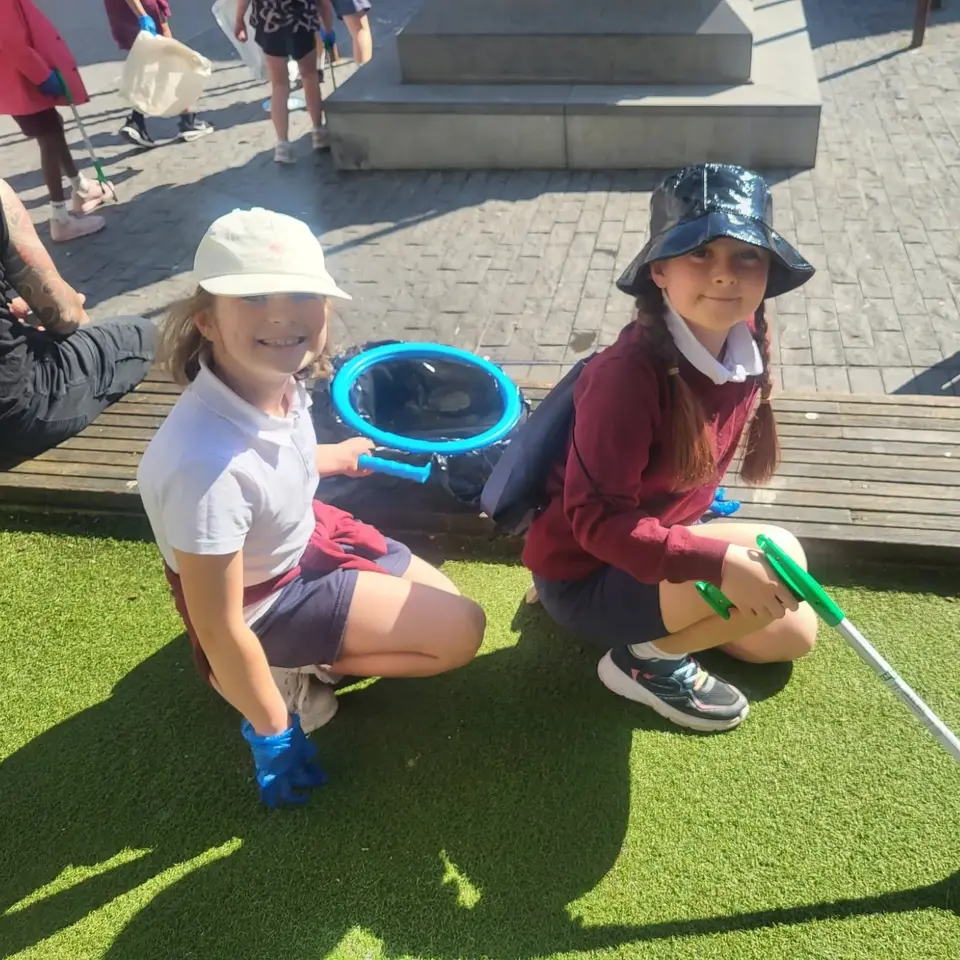 Two pupils with a litter picker and bag during a clean-up in the town