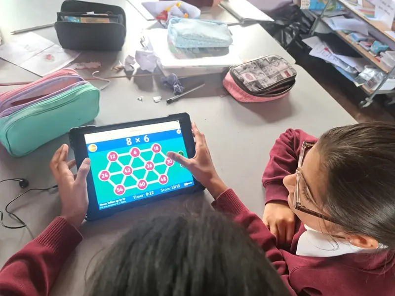 Pupils playing a times tables game on a tablet