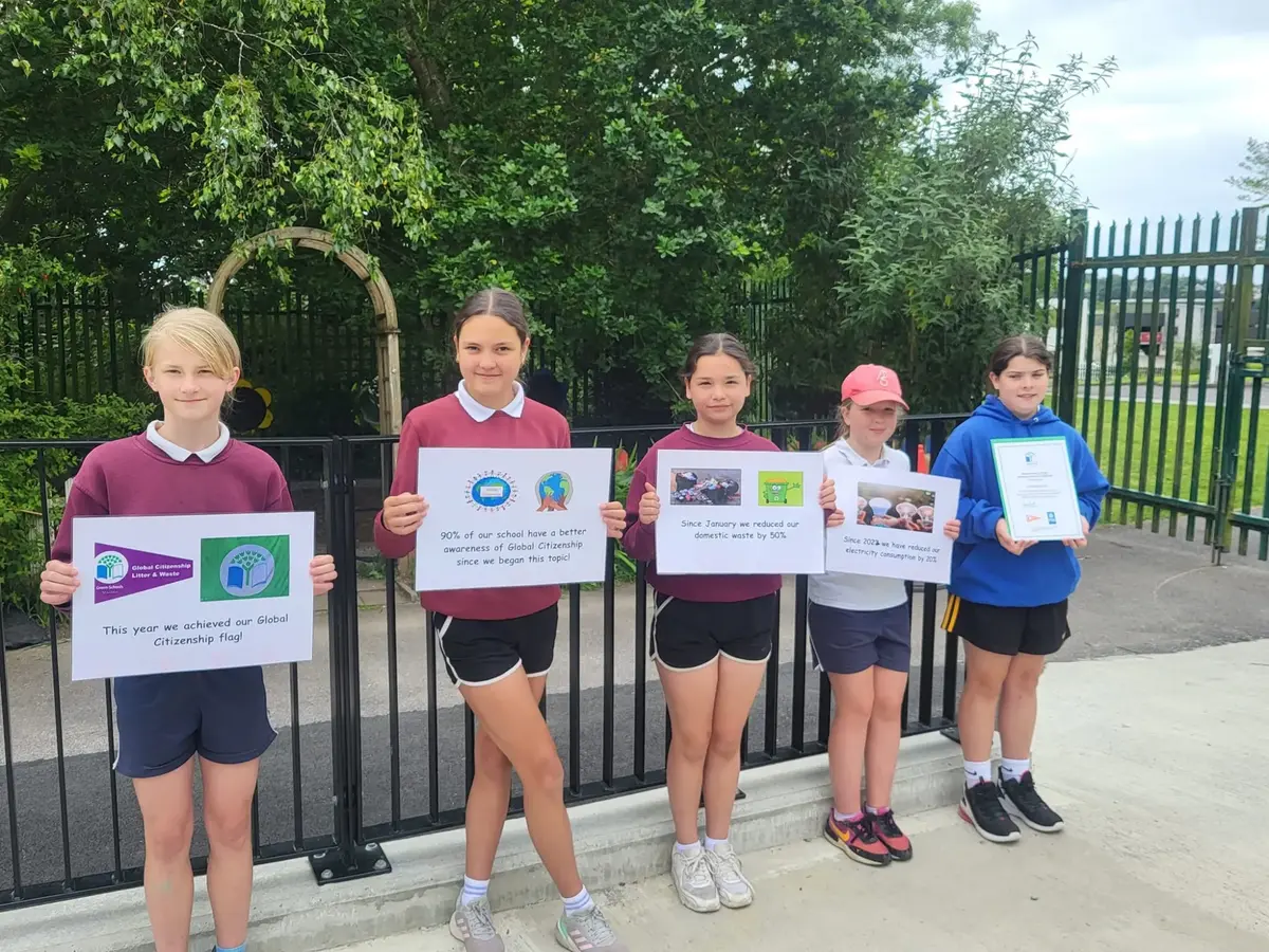 Pupils holding signs about the school’s Global Citizenship Green Flag, including a 50% cut in waste
