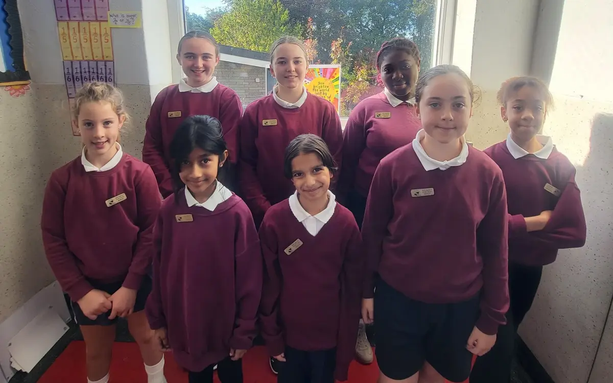 The 2026/27 Student Council: eight pupils in school uniform standing in front of a classroom window