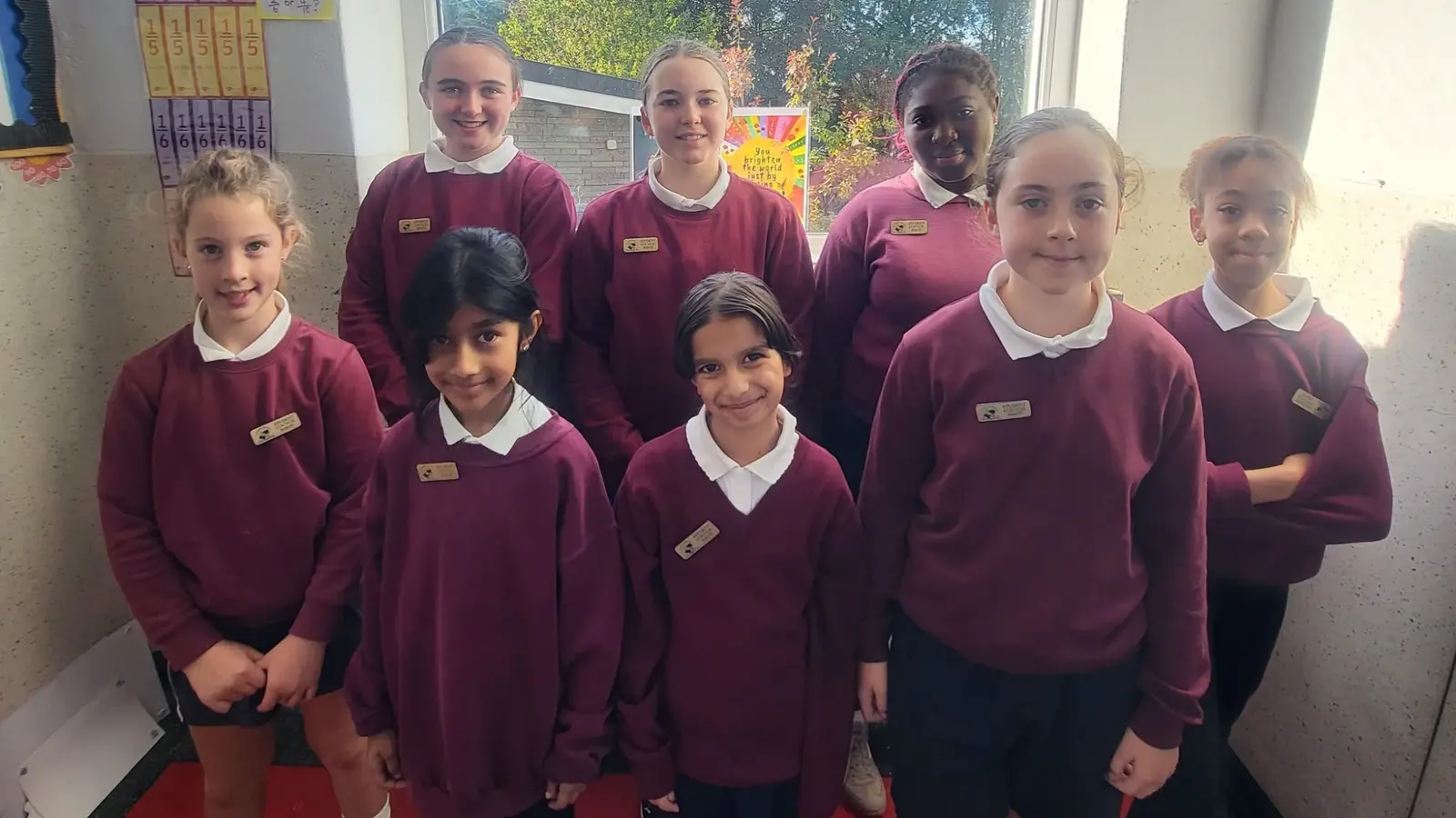 The 2026/27 Student Council: eight pupils in school uniform standing in front of a classroom window