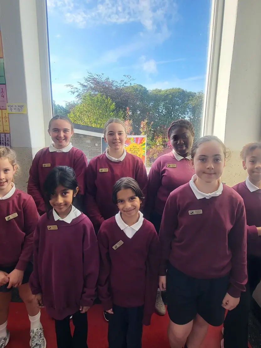 The 2026/27 Student Council: eight pupils in school uniform standing in front of a classroom window