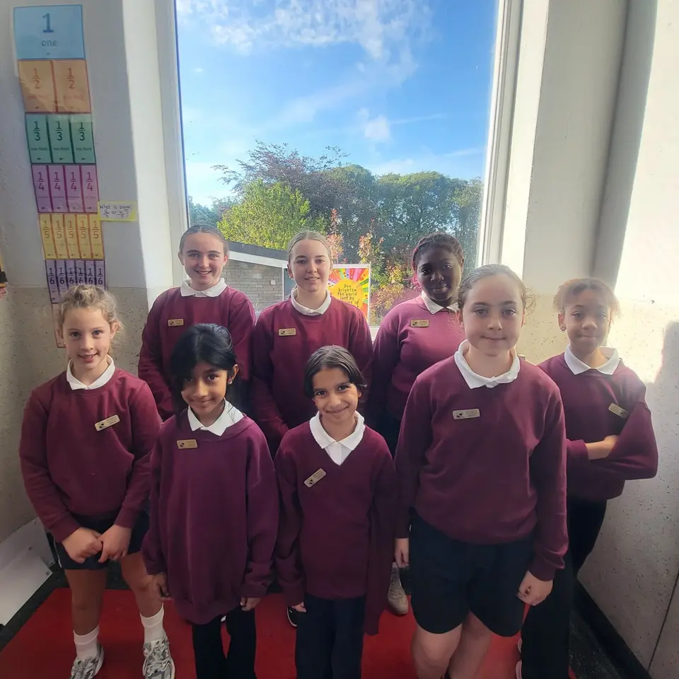 The 2026/27 Student Council: eight pupils in school uniform standing in front of a classroom window