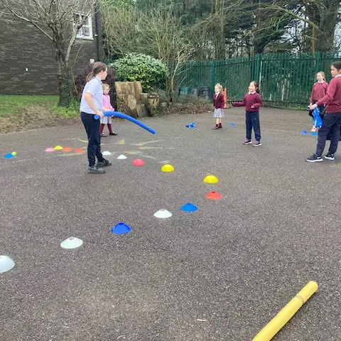1st and 2nd Class pupils doing movement activities at stations in the school yard