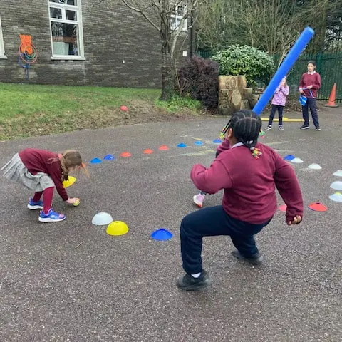 1st and 2nd Class pupils doing movement activities at stations in the school yard