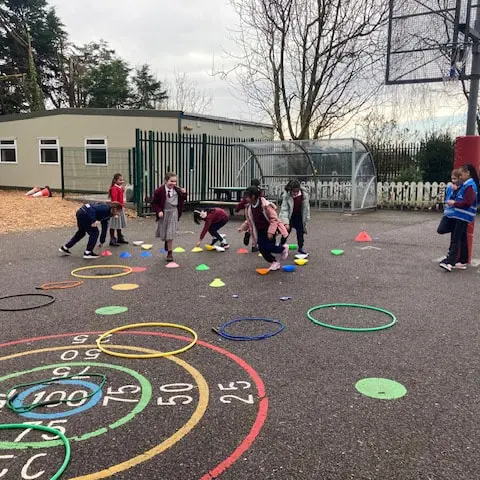 1st and 2nd Class pupils doing movement activities at stations in the school yard
