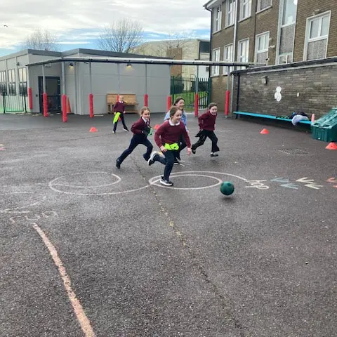 1st and 2nd Class pupils doing movement activities at stations in the school yard