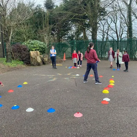 1st and 2nd Class pupils doing movement activities at stations in the school yard