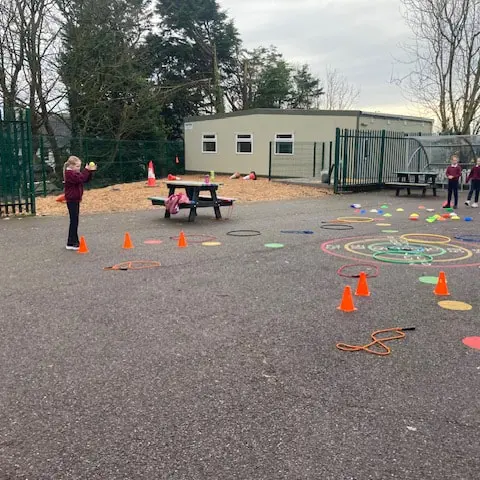 1st and 2nd Class pupils doing movement activities at stations in the school yard