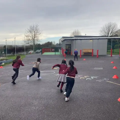1st and 2nd Class pupils doing movement activities at stations in the school yard