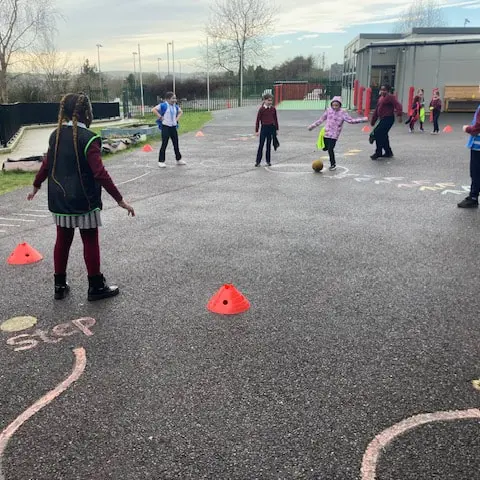 1st and 2nd Class pupils doing movement activities at stations in the school yard