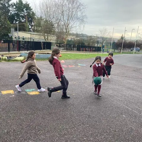 1st and 2nd Class pupils doing movement activities at stations in the school yard